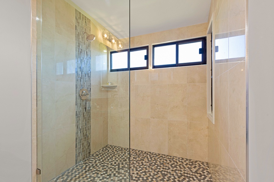 This spacious walk-in shower boasts elegant tile work and a modern glass enclosure