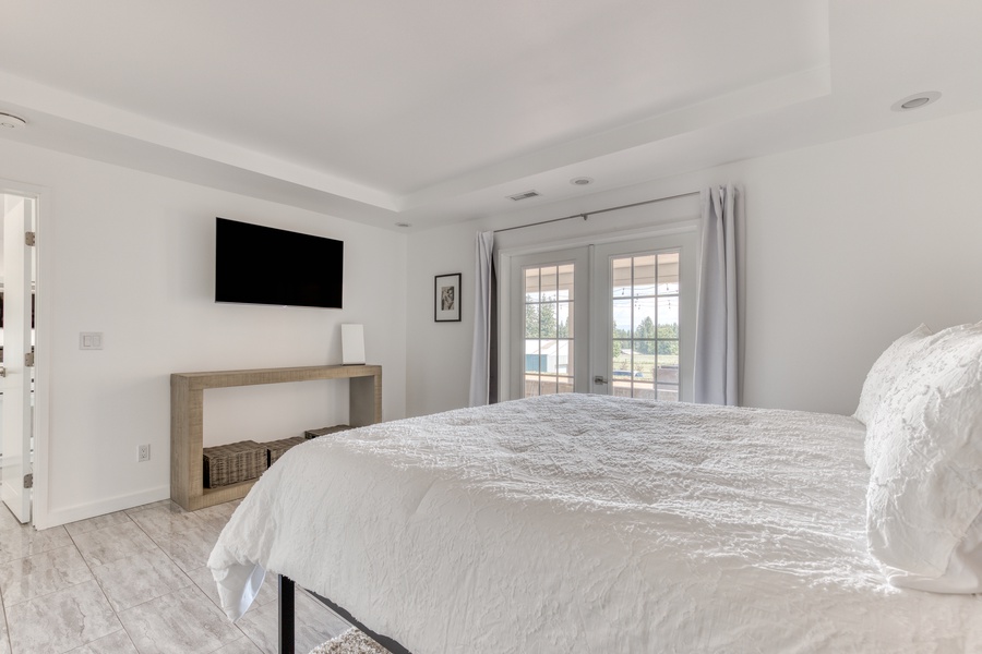 Primary bedroom is spacious and connected to patios through french doors