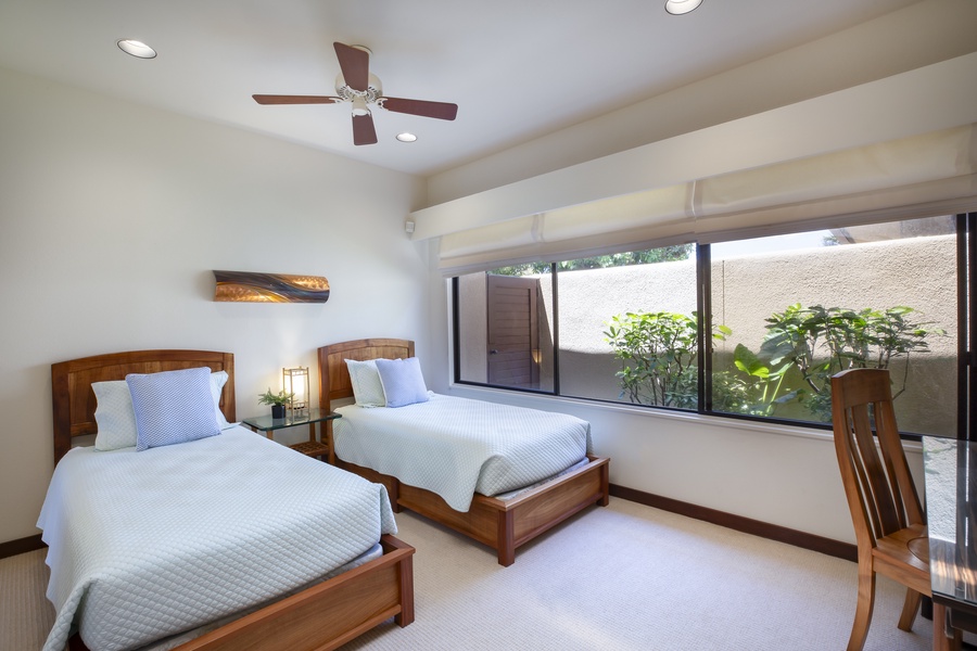 Cozy third bedroom with vaulted ceilings, ceiling fan, and twin beds—ideal for younger guests or friends sharing.