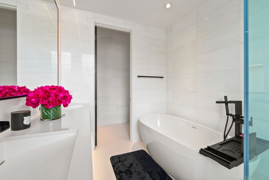 Indulge in your private spa sanctuary with a luxurious freestanding tub, elegant marble walls, and fresh flowers welcoming you home.