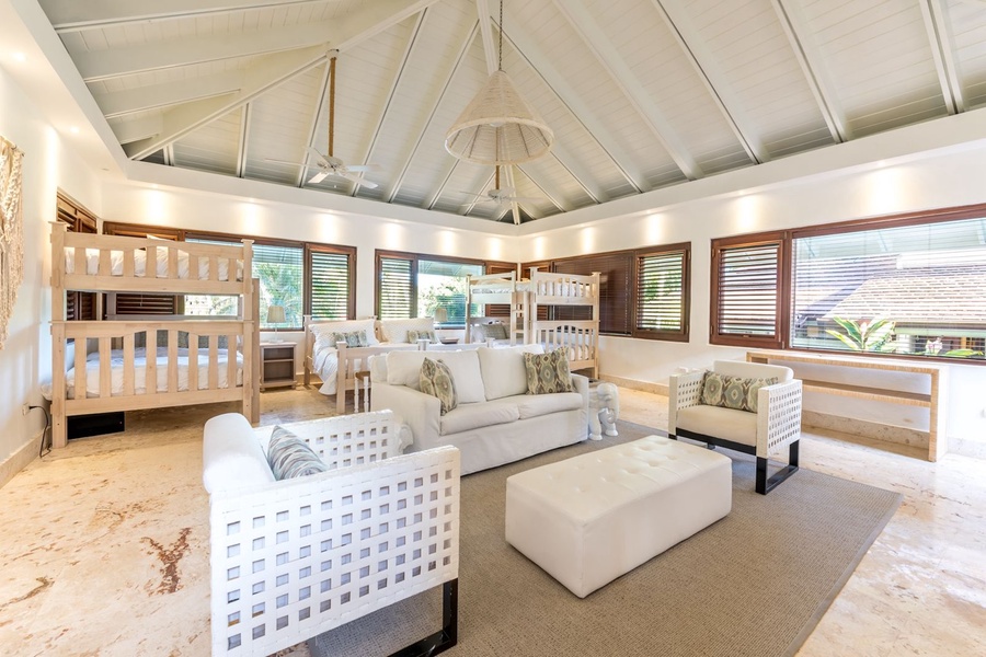 Spacious kids' room with comfortable bunk beds, plush white sofas, and a vaulted ceiling with ceiling fans.