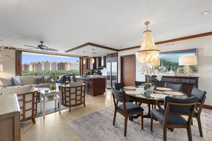 Your elegant open-concept living space flows seamlessly from kitchen to dining, crowned by a stunning chandelier and expansive windows framing resort views.