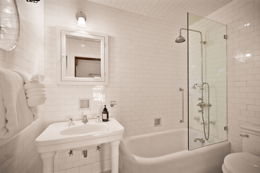 Clean and classic, this white bathroom has a soaking tub, rainfall shower, and everything you need to unwind.