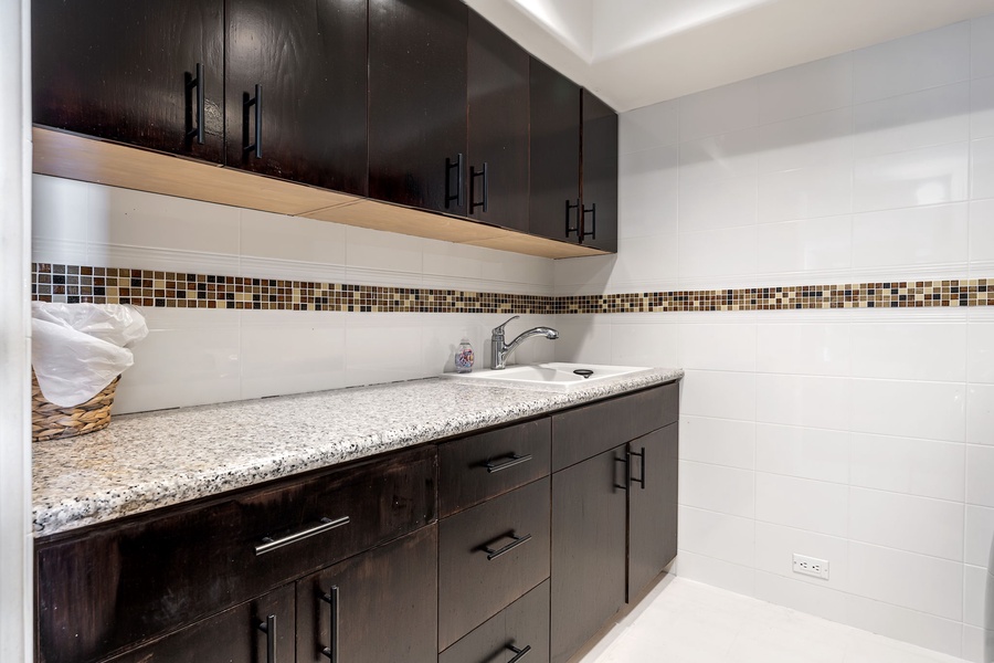 Your spacious laundry features sleek dark cabinets, granite countertops, and mosaic tile accents for effortless meal prep.