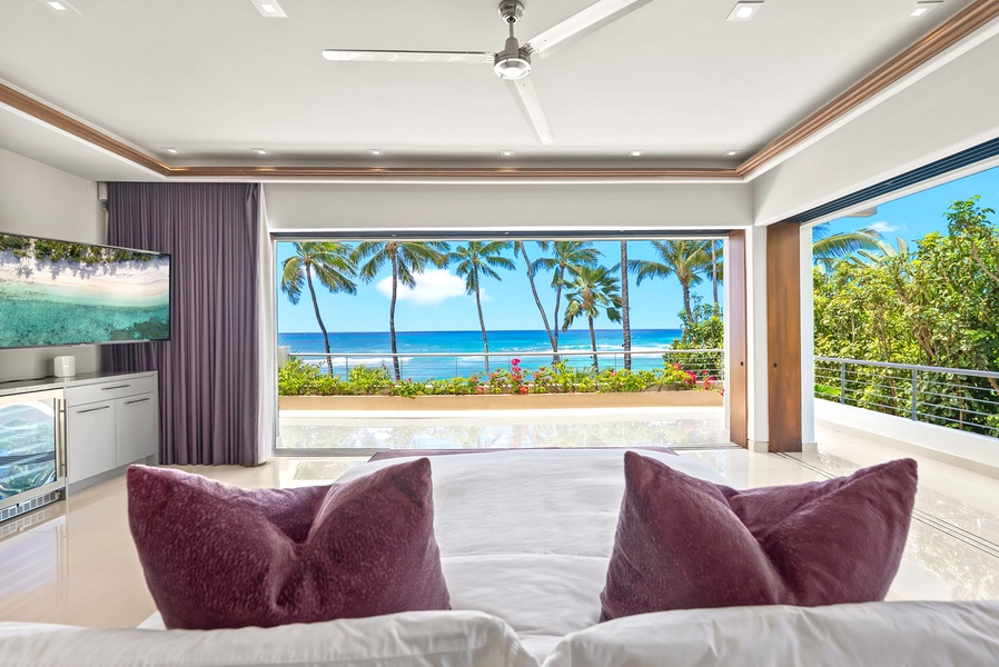 Sink into plush seating as you gaze out at swaying palms and turquoise waters framing your private tropical paradise, where modern elegance meets beachfront bliss.