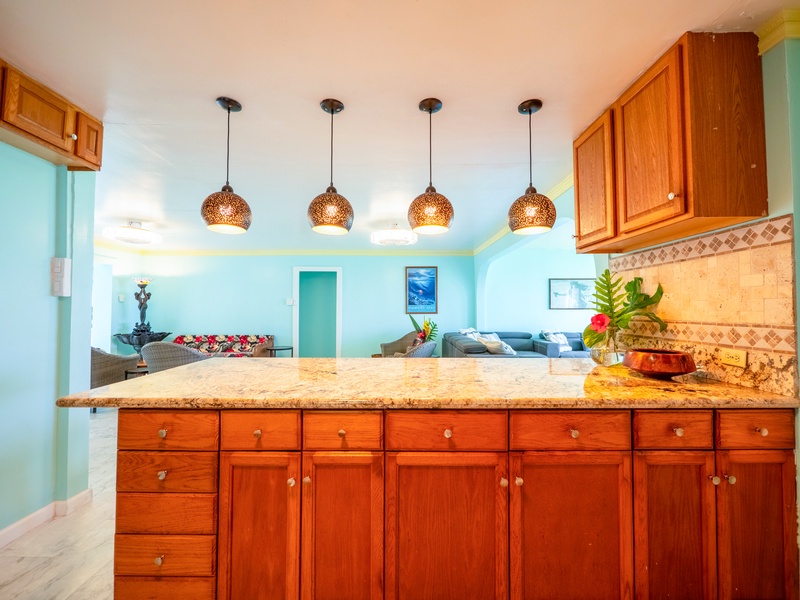 Step into your tropical kitchen paradise with warm wood cabinets, granite counters, and coastal pendant lighting creating the perfect space for your vacation meals.