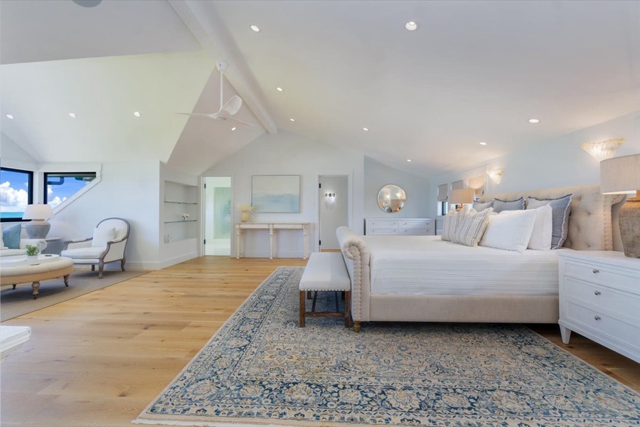 Spacious primary suite with a king bed, natural wood floors, and beachy elegance.