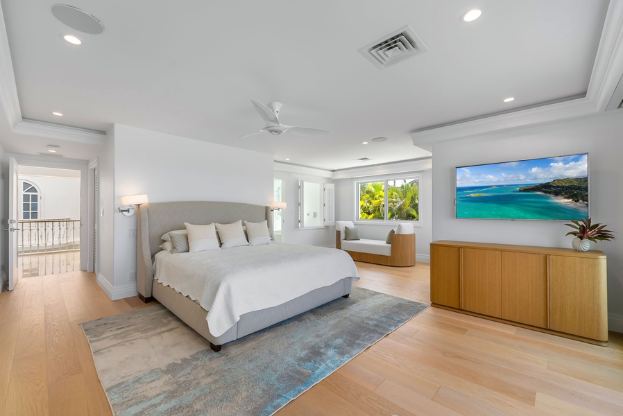 Relax in the bright and airy primary suite, featuring warm wood floors, coastal décor, and beach views.