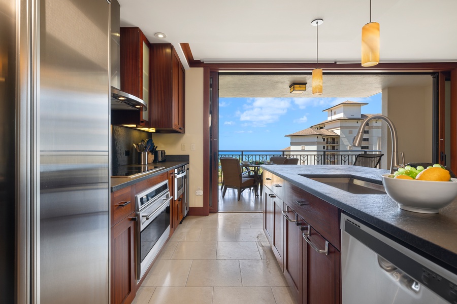 A full kitchen and open floor plan look directly toward the ocean with stainless steel appliances.