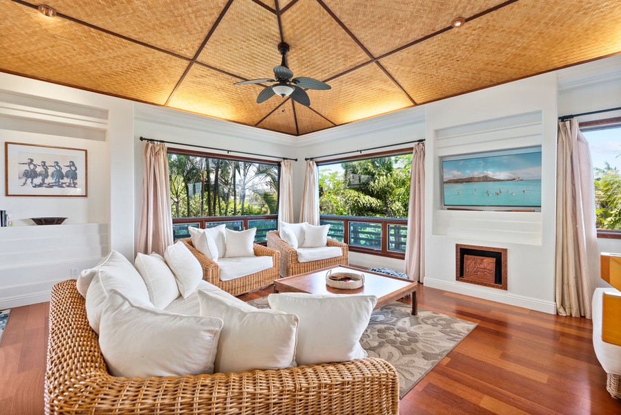 Lounge in the upper-level living area featuring the woven bamboo ceiling with ceiling fan, the wicker sofas with thick, comfortable white cushions and TV, giving the room a tropical and relaxed vibe.