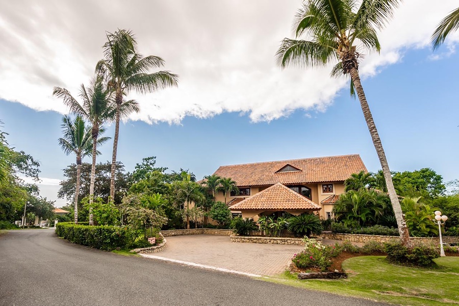 Charming driveway of the estate, surrounded by lush greenery and palm trees.