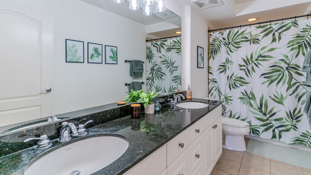 The bright second guest bathroom featuring a shower and Hawaiian greenery.