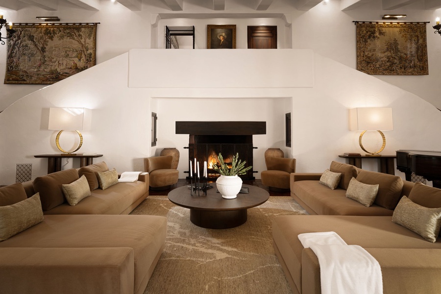 Sink into plush seating around the crackling fireplace, where warm light and rich tapestries create your perfect retreat.