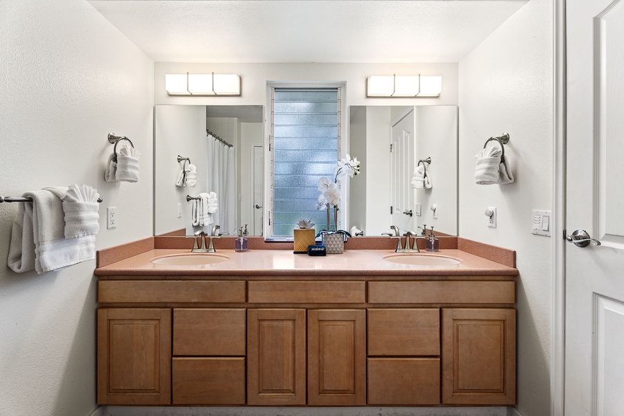 Unwind in your spacious bathroom featuring dual vanities and warm wood cabinetry—perfect for your morning routine.