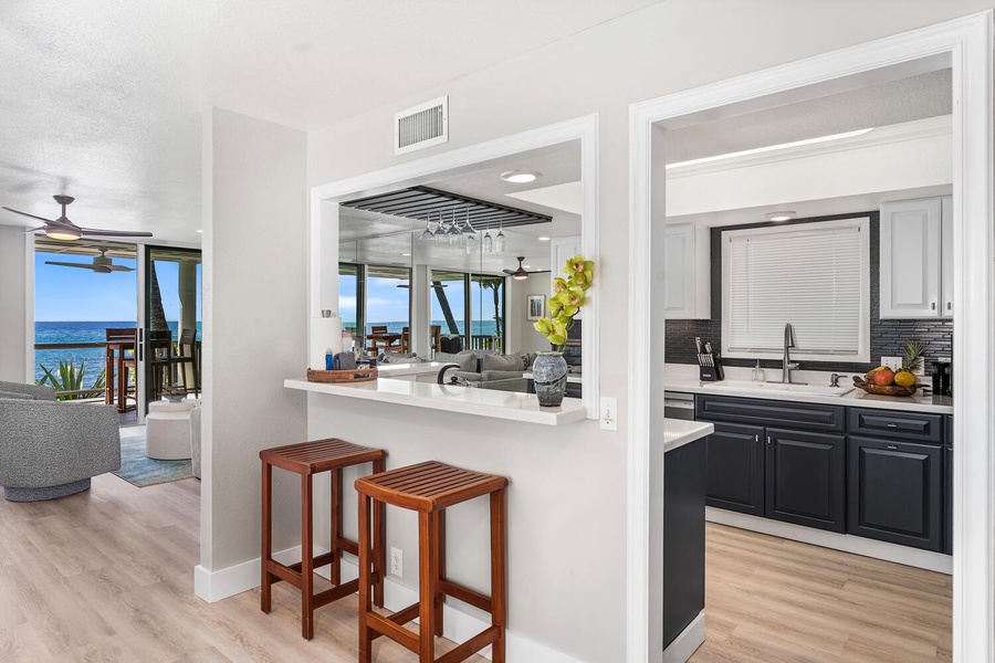 Kitchen pass-through bar with two stools and peek-a-boo ocean views beyond.