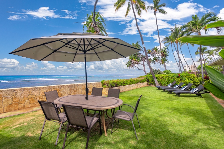 Oceanfront dining lawn with umbrella seating—perfect for al fresco meals with Diamond Head views.