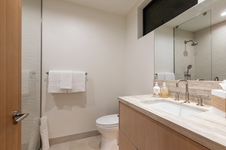 Refresh in your modern bathroom with marble countertops, rainfall shower, and luxury amenities thoughtfully arranged for your comfort.