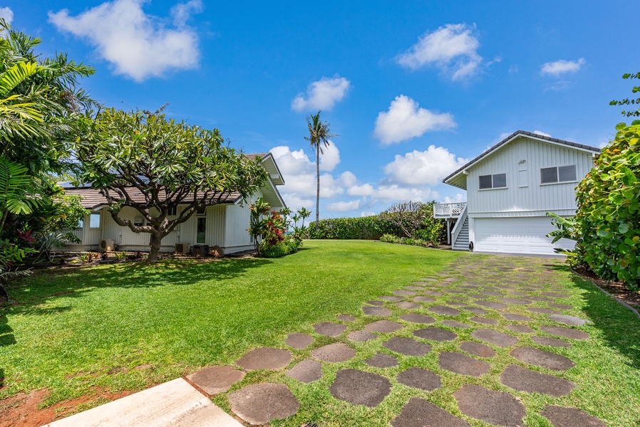 Tropical property featuring lush landscaped grounds with palm trees and expansive lawn areas under clear blue skies.