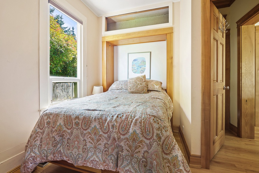 Your cozy Murphy bed unfolds into a peaceful retreat with soft paisley linens and natural light streaming through windows.