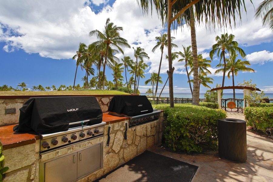 BBQ grills under lush green palm trees.