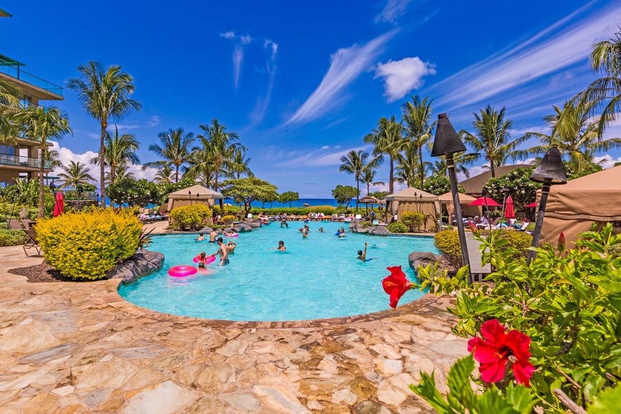 This vibrant pool area, framed by palm trees and colorful flowers, invites guests to relax and play.