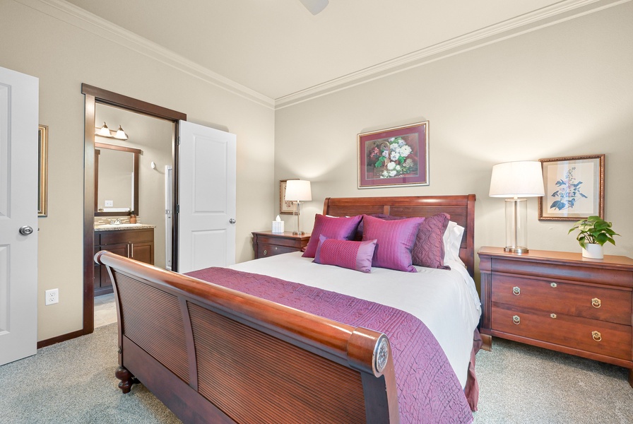Unwind in the spacious primary suite featuring a plush queen bed, ceiling fan, and a private ensuite bath.