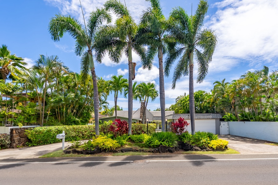 The property sits in a lush tropical neighborhood framed by towering palms and vibrant landscaping, offering a warm welcome to your island getaway.