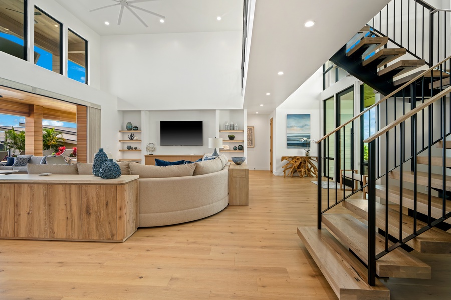 Relax in your stunning open-concept living space with soaring ceilings, modern fireplace, and sleek staircase creating the perfect Kaua'i retreat.