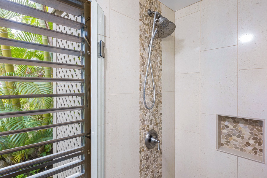 The walk-in shower features a modern rain showerhead and a stylish stone tile accent wall, creating a spa-like experience.