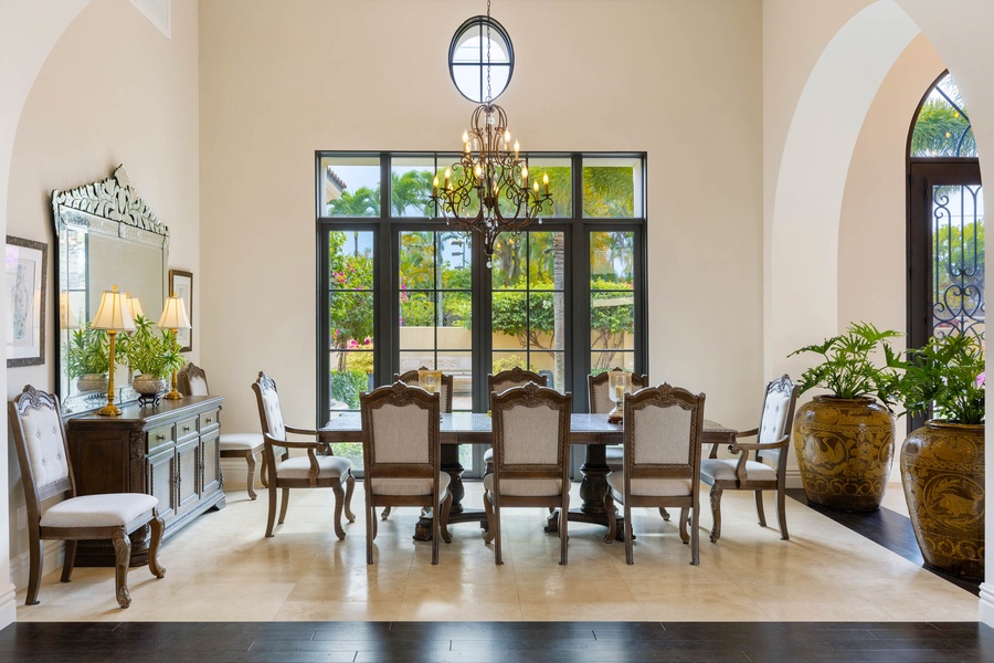 Formal dining room with a grand chandelier, large windows, and seating for memorable meals.