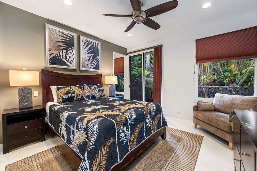 Unwind in your tropical-themed bedroom featuring a ceiling fan, plush furnishings, and serene garden views through your private windows.