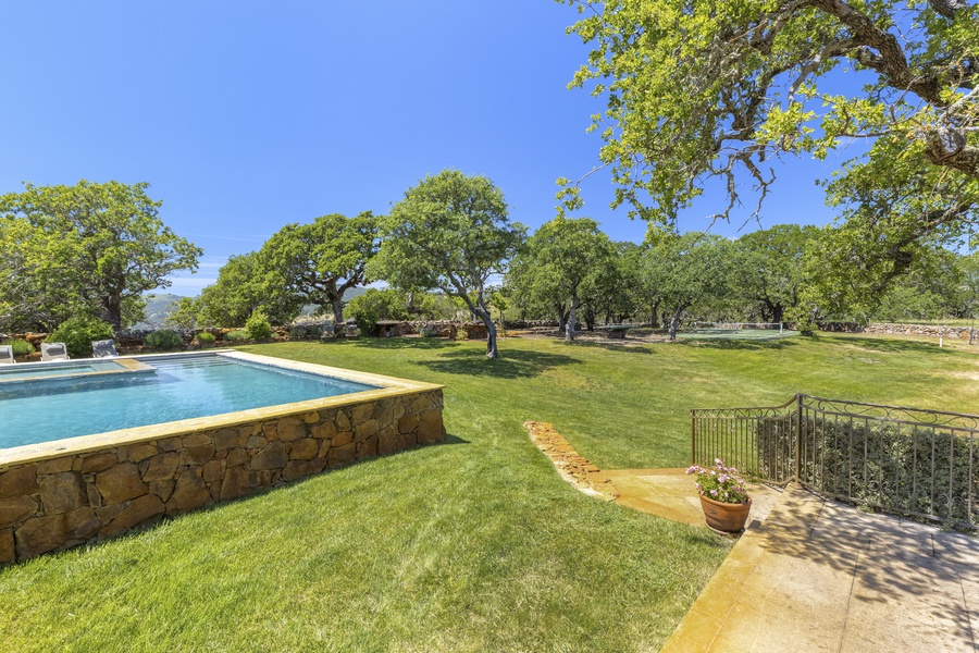 Surrounding the pool and jacuzzi is a pickle ball court, a bocce ball court, a large outdoor shower, cricket, horseshoes, stone seating, a BBQ, and more