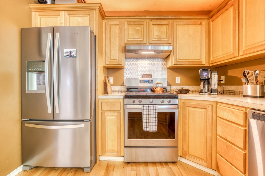 The spacious kitchen is outfitted with several stainless steel appliances and a large countertop with bar stools for easy meal prep and entertaining while cooking