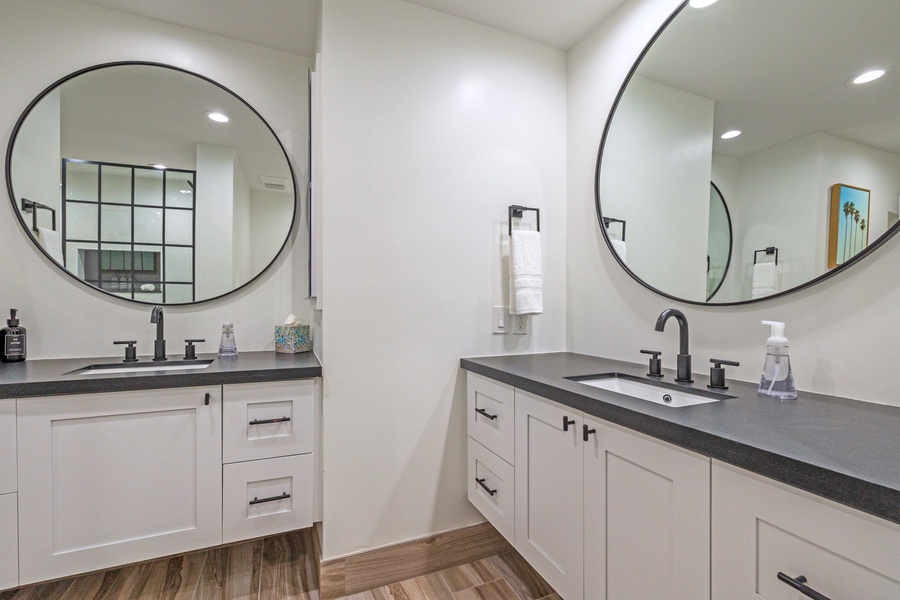 This double vanity bathroom features sleek black fixtures and large round mirrors, creating a modern and functional space for getting ready