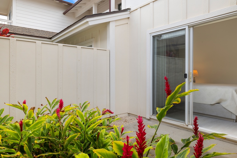 A private outdoor patio off the primary suite, lined with lush tropical greenery for serene moments.