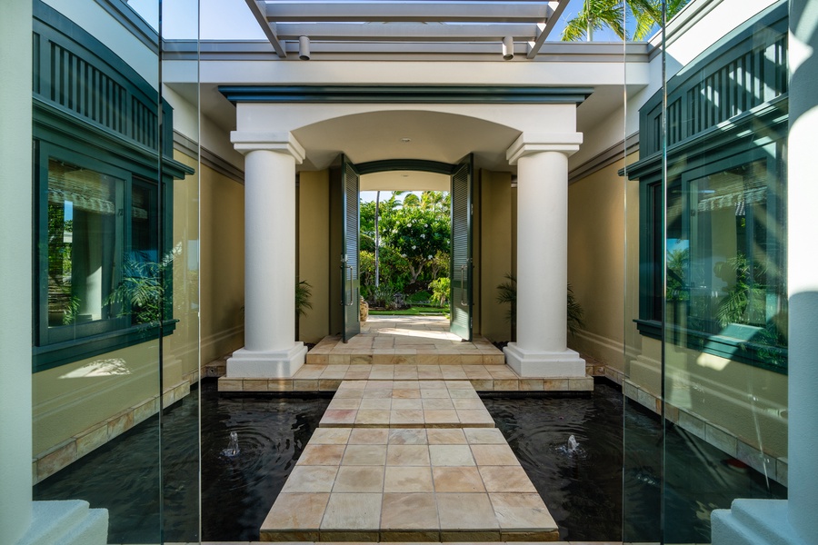 Grand entrance with stately columns and a walkway over water features.