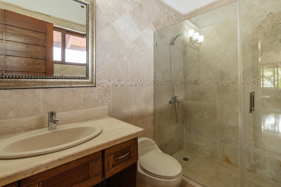 Modern ensuite bathroom features a natural stone finishes and a spacious shower.