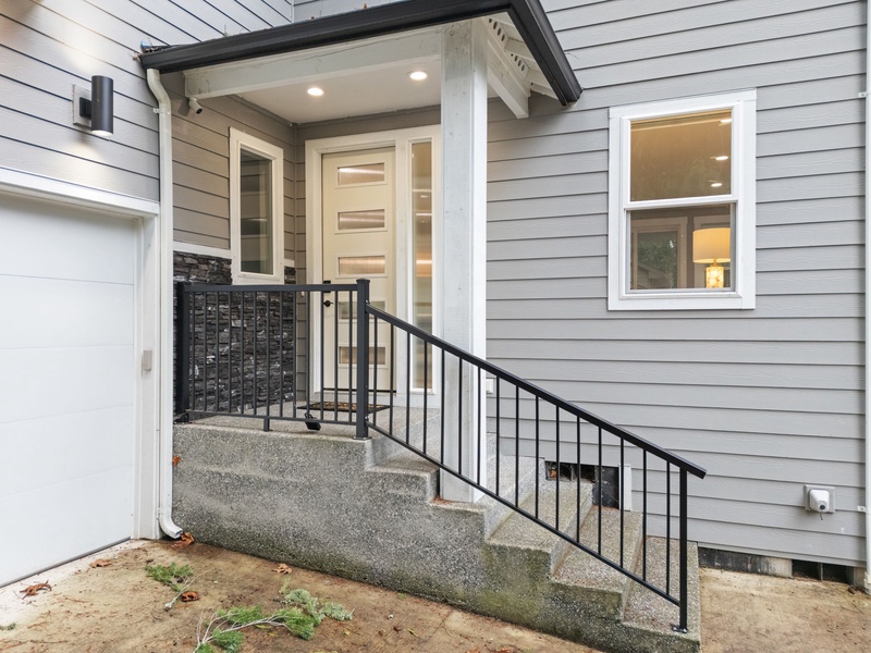 Welcoming covered porch, contemporary design, and well-lit entry area.