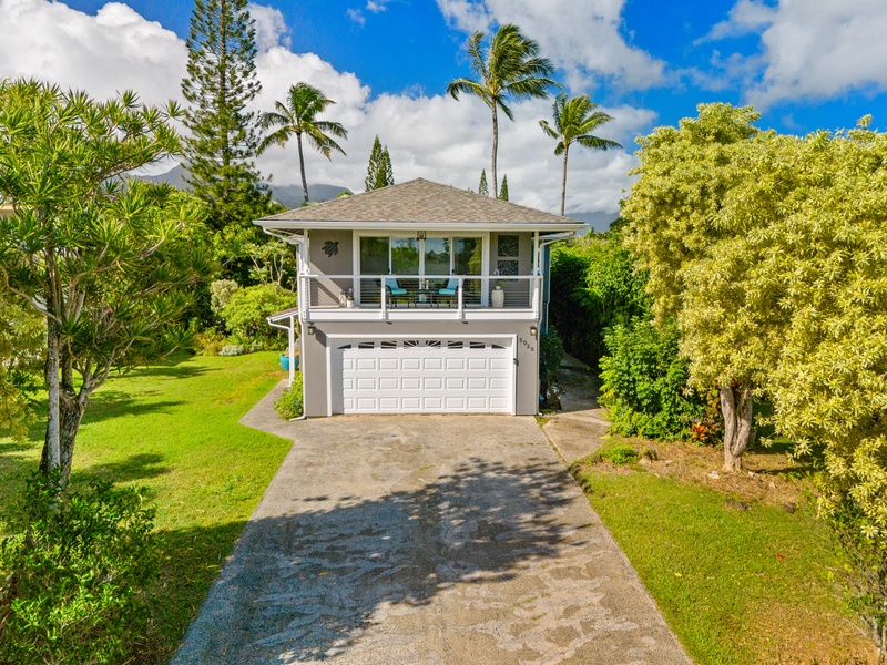 Beautiful home exterior with a private driveway, surrounded by lush greenery and tropical landscaping.