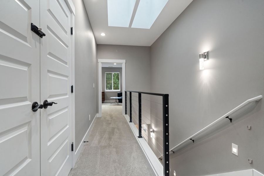A bright, modern hallway with skylight above guides you to comfortable spaces ahead.