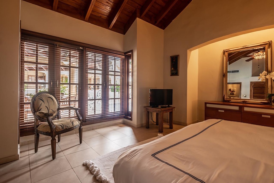 Relax in guest bedroom with large wooden doors and enjoy the outside view.