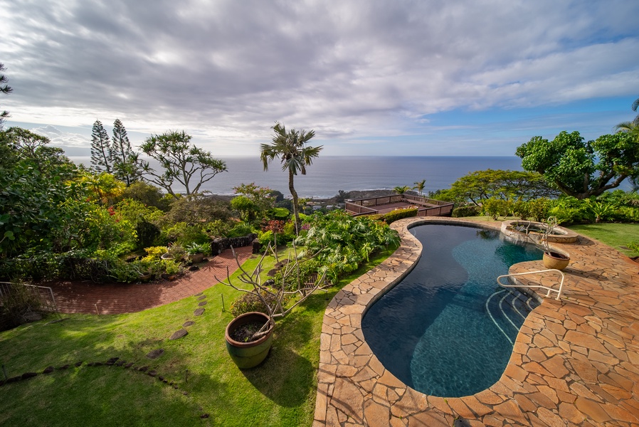 Elevated ocean view property featuring a curved swimming pool surrounded by lush tropical gardens with panoramic sea views.
