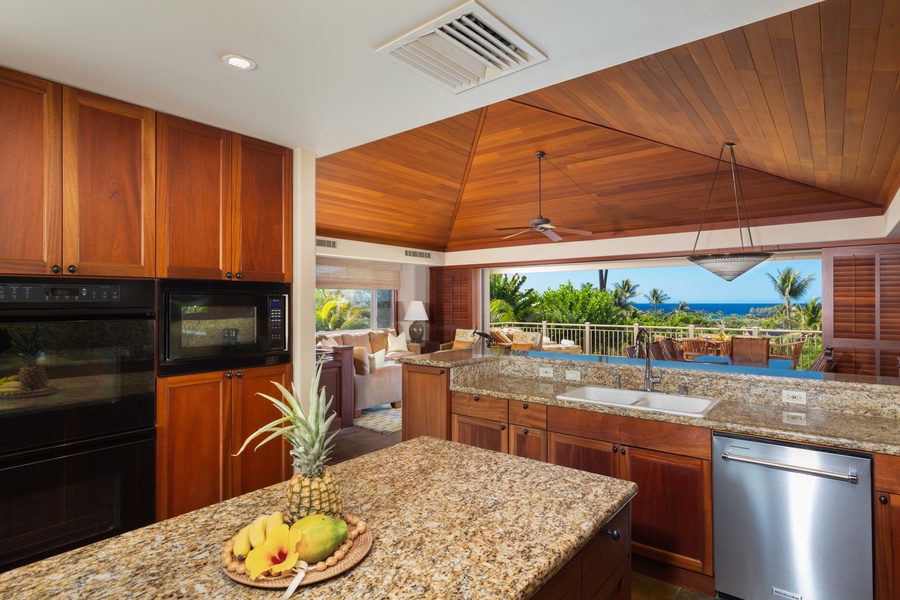 Ocean view kitchen with gleaming granite countertops and top tier appliances.