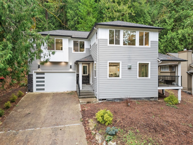 Modern two-story home nestled among towering evergreens with contemporary design and welcoming entrance.