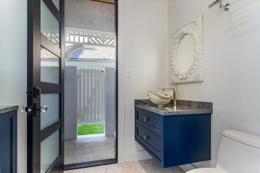 Powder room with stylish vanity and direct exterior access for pool convenience.