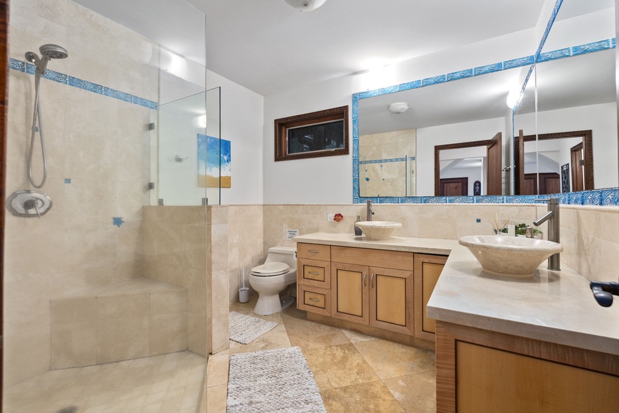 A full bathroom with a large shower and double sinks serves the downstairs area.