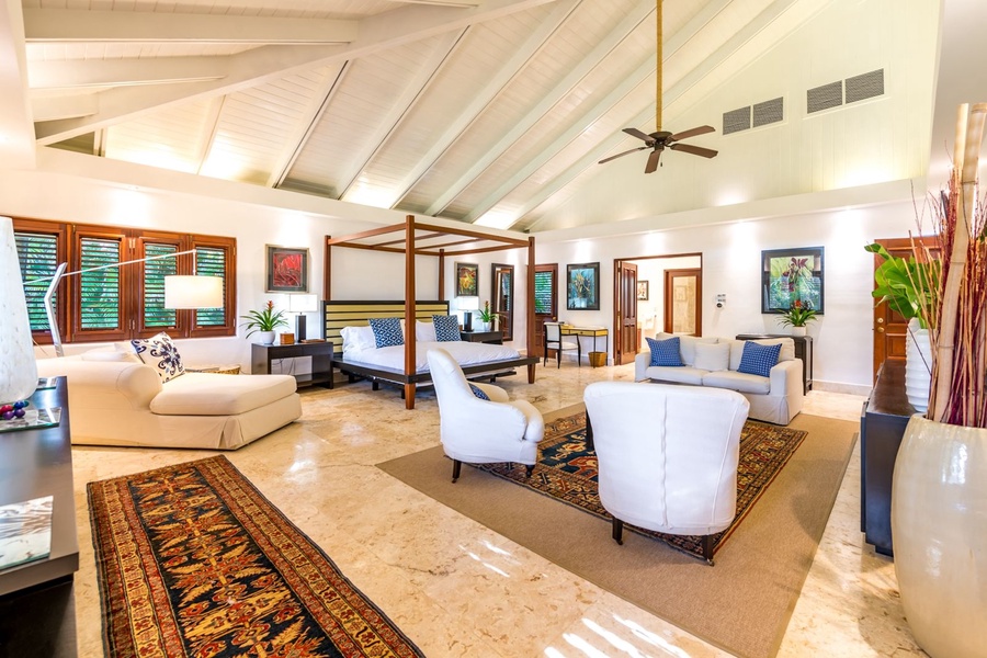 Spacious primary bedroom with a plush bed and ample seating.