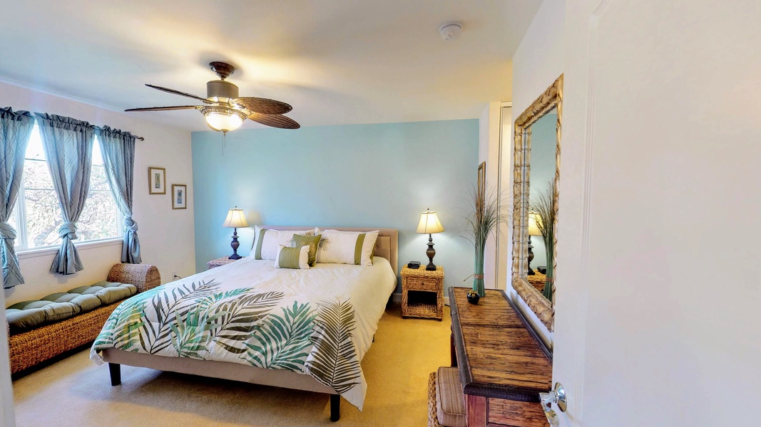 The primary guest bedroom featuring soft linens and a ceiling fan.