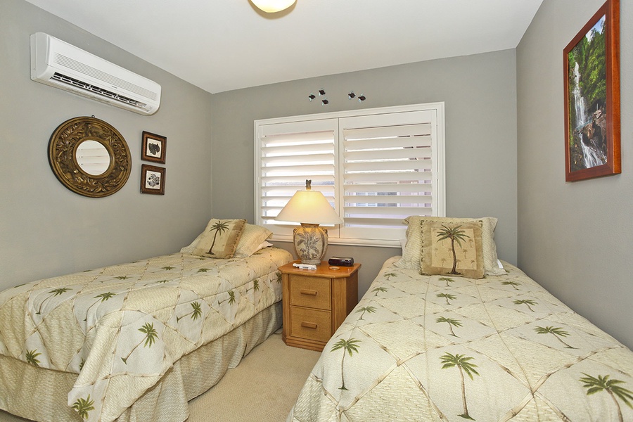 The third guest bedroom features twin beds and delicate palm decor.