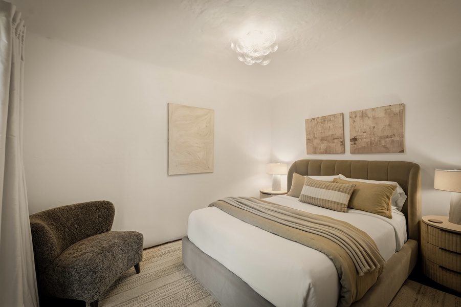 Sink into your cozy haven with warm earth tones, soft lighting, and a plush upholstered headboard for perfect relaxation.